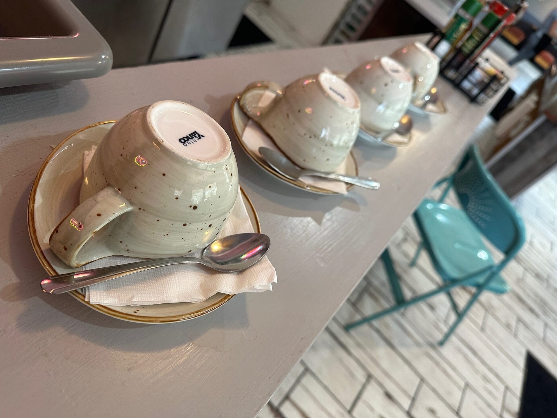 Three speckled ceramic coffee cups on saucers along the counter