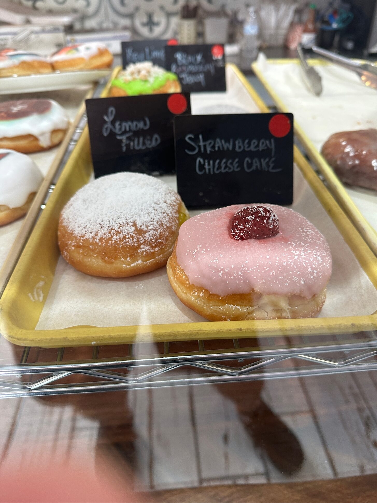 Bakery display case with lemon filled and strawberry cheesecake donuts