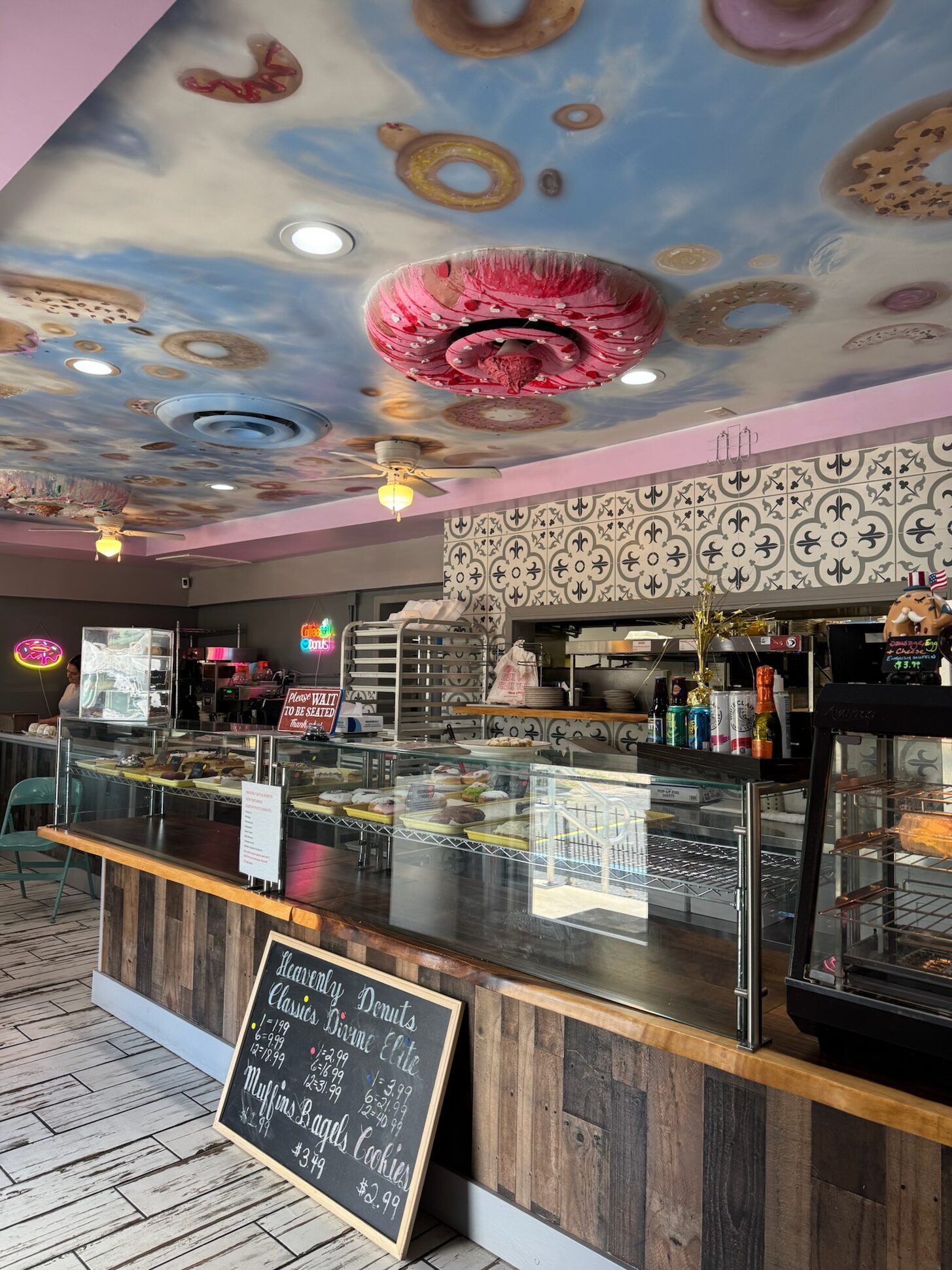 Inside Heavenly Eats and Sweets showing the bakery counter with hand-painted donut ceiling mural and decorative tile